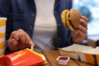 Lviv, Ukrayna - 9 Ekim 2023: Restorandaki ahşap masada McDonald 's menüsü olan kadın, yakın plan