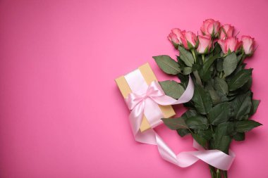 Hediye kutusu ve pembe arka planda güzel çiçekler. Metin için boşluk