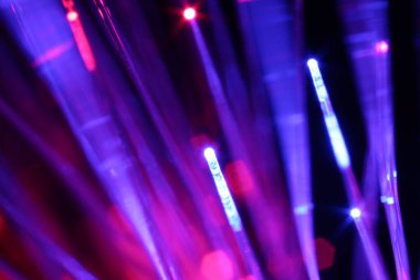 Optik fiber iplikler siyah arkaplan üzerinde farklı renk ışıkları iletiyor, makro görünüm