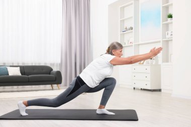 Son sınıf öğrencisi kadın evde yoga yapıyor.