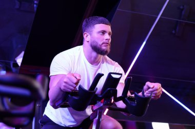 Spor salonunda spor bisikleti eğitimi alan genç bir adam.