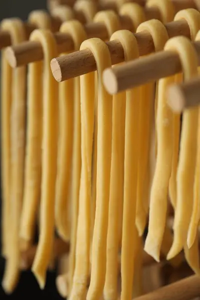 Homemade pasta drying on wooden rack, closeup