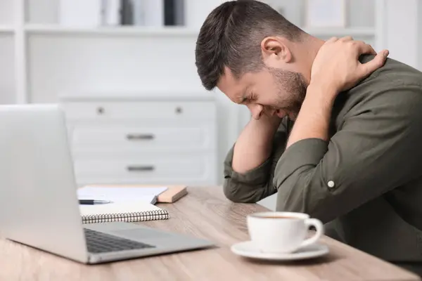 Man suffering from neck pain in office