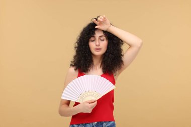 El fanı olan kadın bej arka planda ısıdan muzdarip.