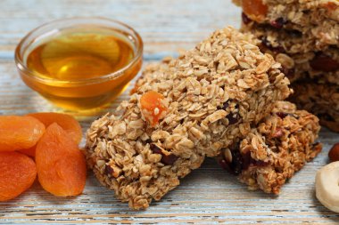 Lezzetli granola barlar ve malzemeler açık mavi ahşap masa üzerinde, yakın plan.
