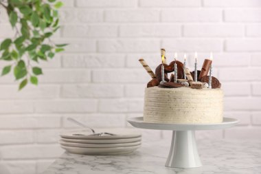 Tatlı ile süslenmiş lezzetli pasta ve beyaz mermer masada yanan mumlar, metin için yer