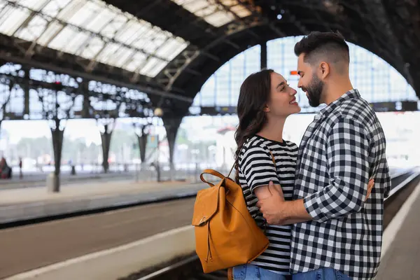 Long-distance relationship. Beautiful couple on platform of railway station, space for text