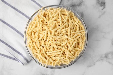 Beyaz mermer masada, kasede pişmemiş trofie makarna.