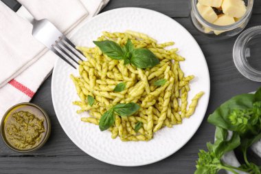Pesto soslu lezzetli trofie makarna ve gri ahşap masa üzerinde fesleğen yaprağı düz yatıyordu.
