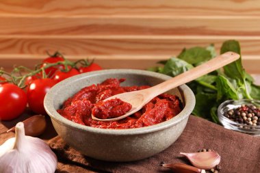 Bir kase lezzetli domates ezmesi, kaşık ve içindekiler masada.