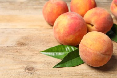 Taze şeftali ve yapraklar ahşap masada, yakın plan. Metin için boşluk