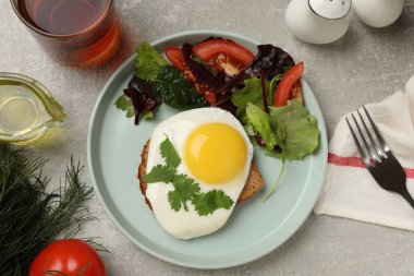 Yağda yumurta ve salatayla nefis bir kahvaltı açık gri masada servis edilir.