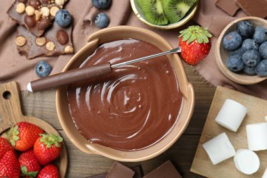 Erimiş çikolatalı fondü tenceresi, marşmelov, taze kivi, farklı böğürtlen ve çatal, ahşap masa, düz yatak.