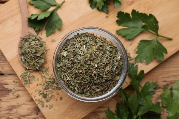 Dried parsley and fresh leaves on wooden table, flat lay