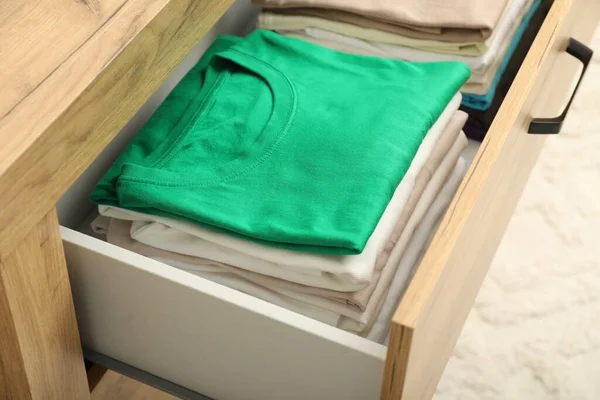 Stacks of different folded shirts in drawer indoors, closeup. Organizing clothes