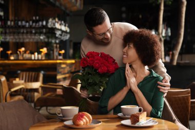 Uluslararası randevu. Yakışıklı bir adam restoranda kız arkadaşına gül sunuyor, mesaj atmak için yer var.