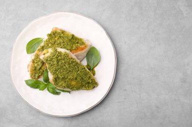 Pesto soslu leziz tavuk göğsü ve açık gri masada fesleğen, üst manzara. Metin için boşluk