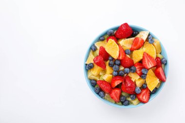 Beyaz arka planda kasede lezzetli meyve salatası, üst manzara. Metin için boşluk