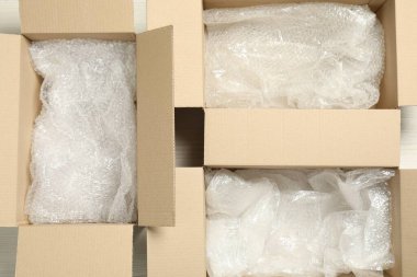 Beyaz ahşap zeminde baloncuk ambalajlı karton kutular, düz yatıyordu.