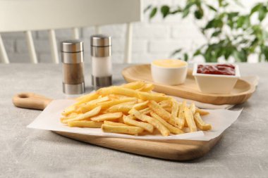 Açık gri masada soslu lezzetli patates kızartması.