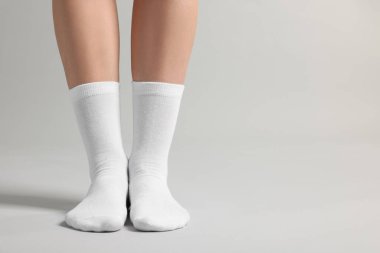 Açık gri arka planda beyaz çoraplı bir kadın, yakın plan. Metin için boşluk