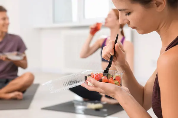 Group of people eating healthy food after yoga class indoors, space for text