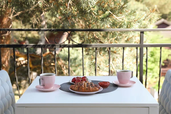 Outdoor breakfast with tea and croissants on white table on terrace