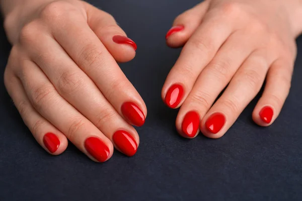 Woman with red polish on nails on black background, closeup