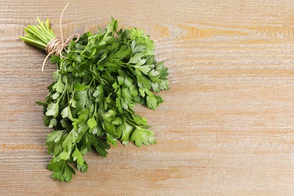Bunch of fresh green parsley leaves on light wooden table. Space for text