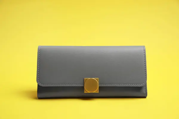 Stylish light grey leather purse on yellow background