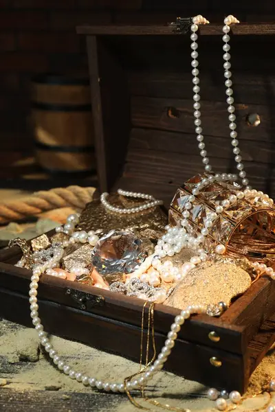 Chest with treasures and scattered sand on wooden table