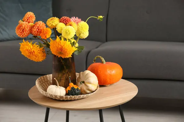 Beautiful autumn bouquet and pumpkins on coffee table near sofa in room