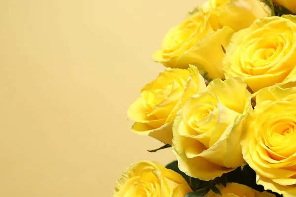 Beautiful bouquet of yellow roses on beige background, closeup. Space for text