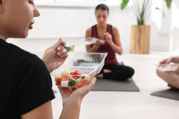 Group of people eating healthy food after yoga class indoors, closeup. Space for text