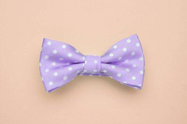 Bej arkaplanda benek desenli mor papyon, üst görünüm