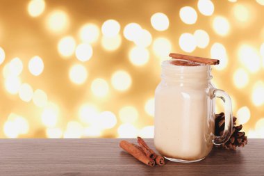 Ahşap masadaki mason kavanozdaki nefis eggnog bulanık Noel ışıklarına karşı, mesaj için yer