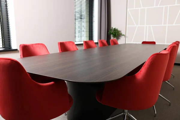 Empty conference room with stylish red office chairs and large wooden table