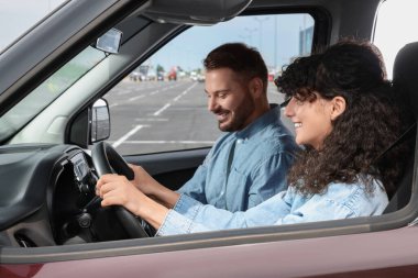 Ehliyet kursu. Otoparkta sürüş eğitmeniyle ders sırasında mutlu öğrenci.