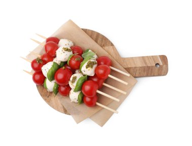 Beyaz arka planda domatesli şişler, mozzarella topları, fesleğen ve pesto sosu.