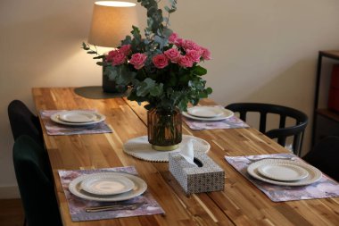 İçinde peçeteler ve buketler olan güzel bir masa. Vazoda gül ve okaliptüs dalları