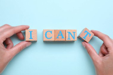 Motivasyon konsepti. Kadın, I Can 'dan I Can' e geçiş cümlesini açık mavi arkaplanda T harfi ile tahta küpü kaldırarak değiştirebilir.