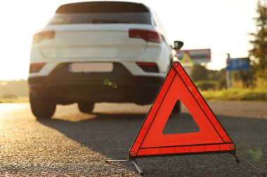 Uyarı üçgeni ve yol kenarındaki kırık araba, seçici odak