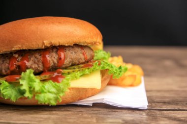 Köfteli lezzetli burger, ahşap masada marul ve peynir, yakın plan. Metin için boşluk