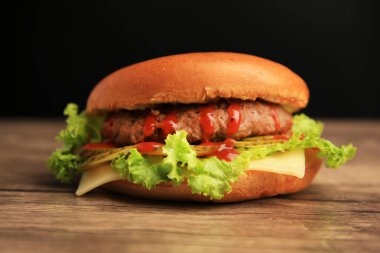 Köfteli lezzetli bir hamburger, ahşap masada marul ve peynir, yakın plan.