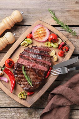 Tahta masada sebzelerle servis edilen leziz kızarmış et.