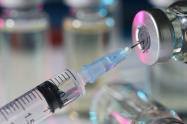 Şırıngayı ilaç şişesiyle dolduruyorum. Arka plan bulanıklaşıyor. Yakın plan.