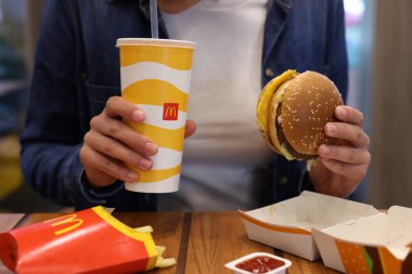 Lviv, Ukrayna - 9 Ekim 2023: Restorandaki ahşap masada McDonald 's menüsü olan kadın, yakın plan
