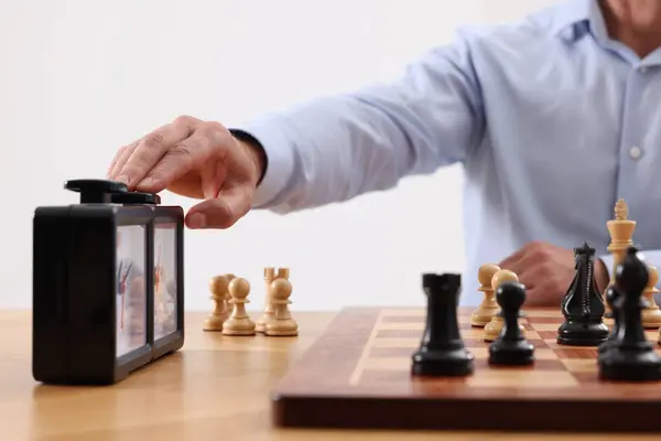 Man turning on chess clock during tournament at table, closeup
