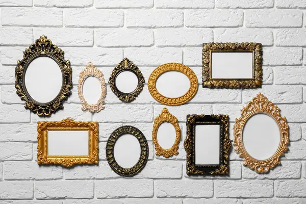 Blank vintage frames hanging on white brick wall. Mockup for design