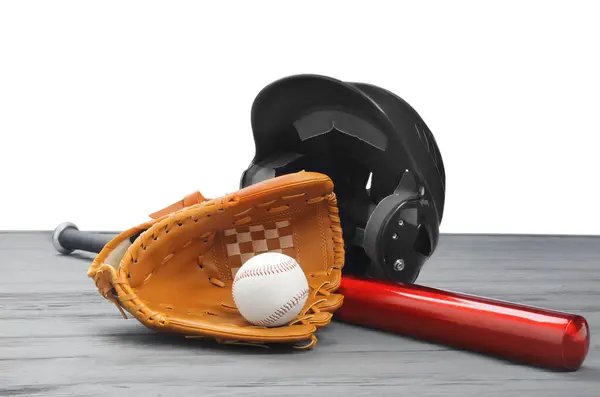 Baseball glove, bat, ball and batting helmet on grey wooden table against white background